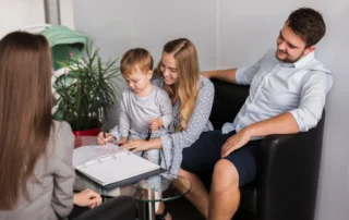 Parents with toddler signing paperwork in office