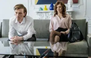 Tense couple sitting apart on living room couch