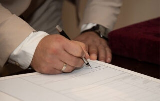 Person signing a document with a pen
