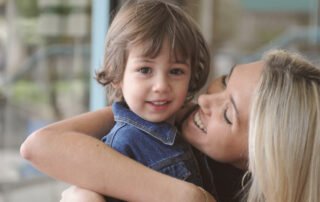 Smiling mother hugs young child indoors