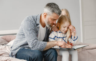 Father reading book with two children on bed
